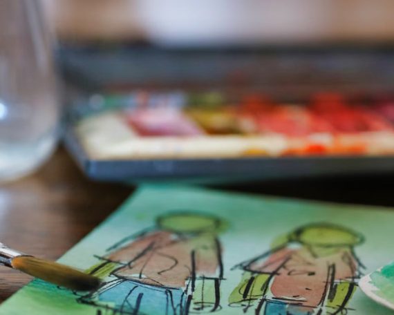 Close-up of watercolor artwork with paintbrushes and palette, showcasing creativity indoors.