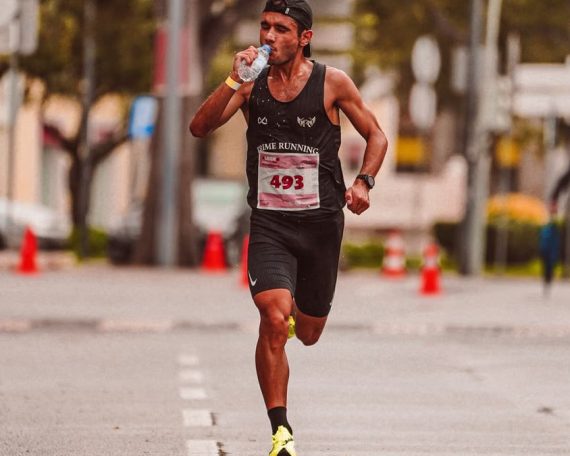 Athlete running in a marathon, staying hydrated. Outdoor city street scene.